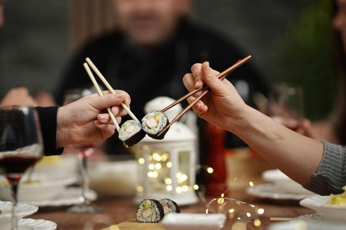 テーブルで箸に乗った寿司を食べている二人