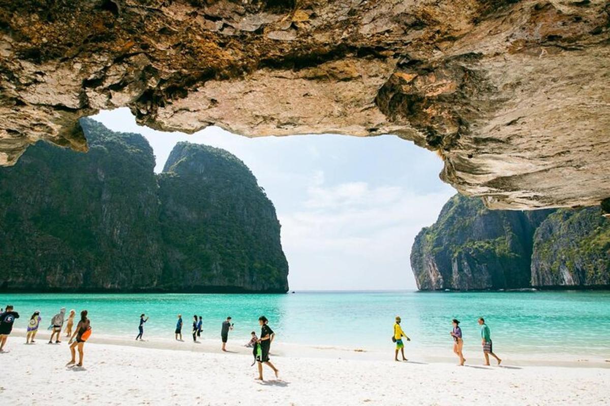 sekumpulan orang berjalan di pantai berhampiran sebuah gua