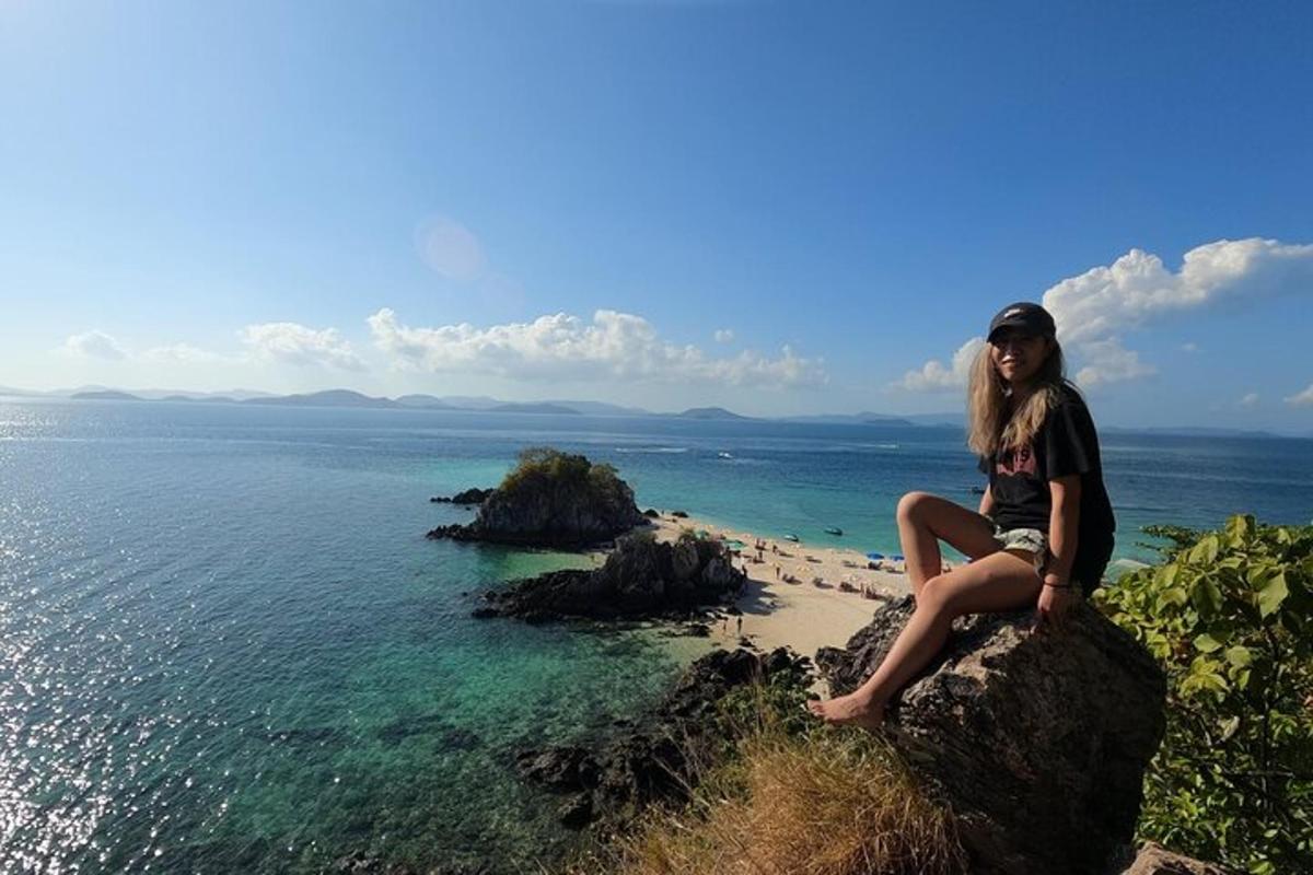 seorang wanita duduk di atas batu yang menghadap ke lautan