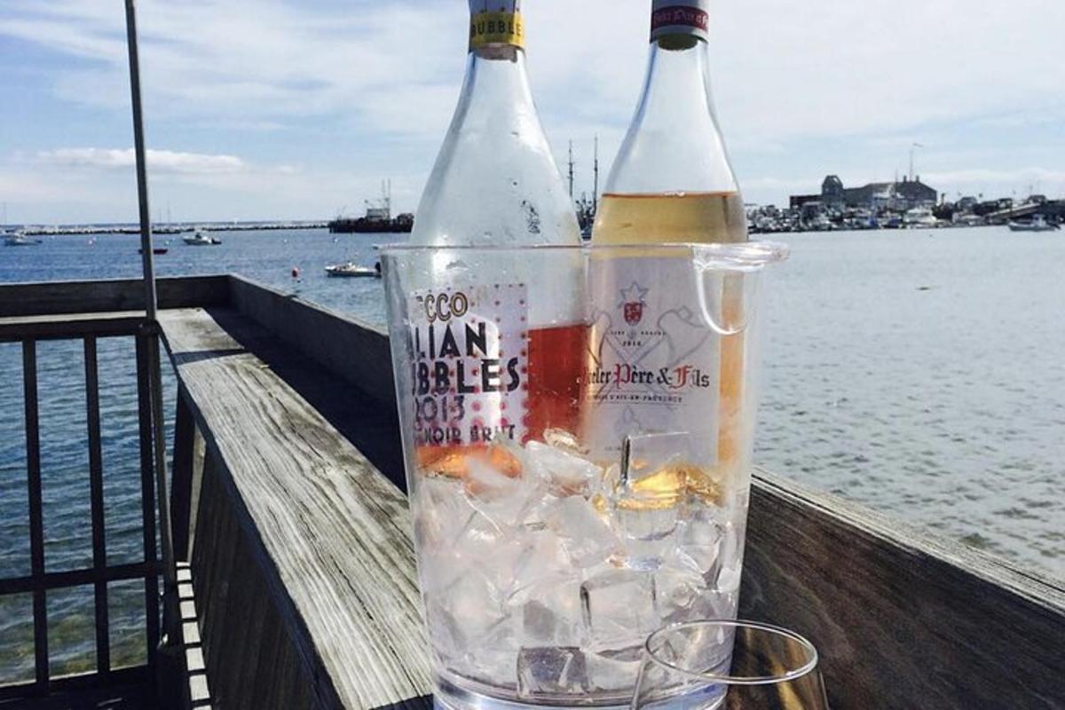 two bottles of alcohol sitting on a rail next to the water