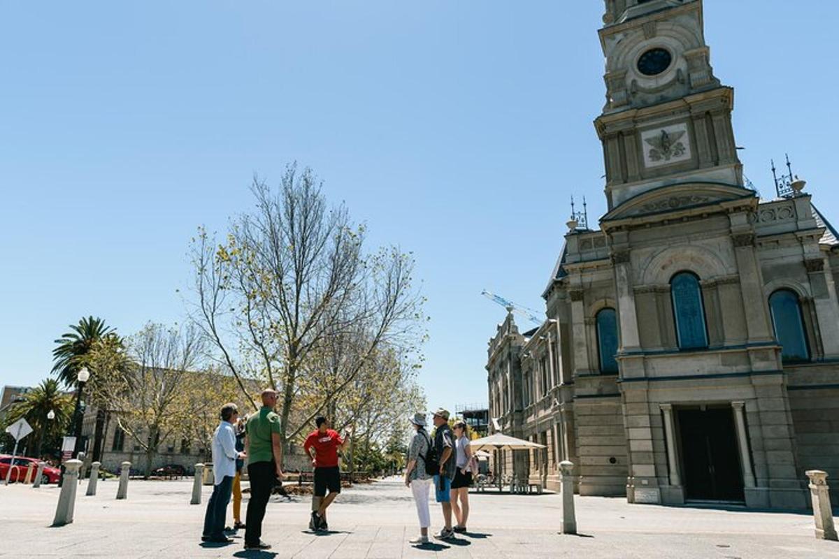 um grupo de pessoas em pé em frente a um prédio com uma torre de relógio