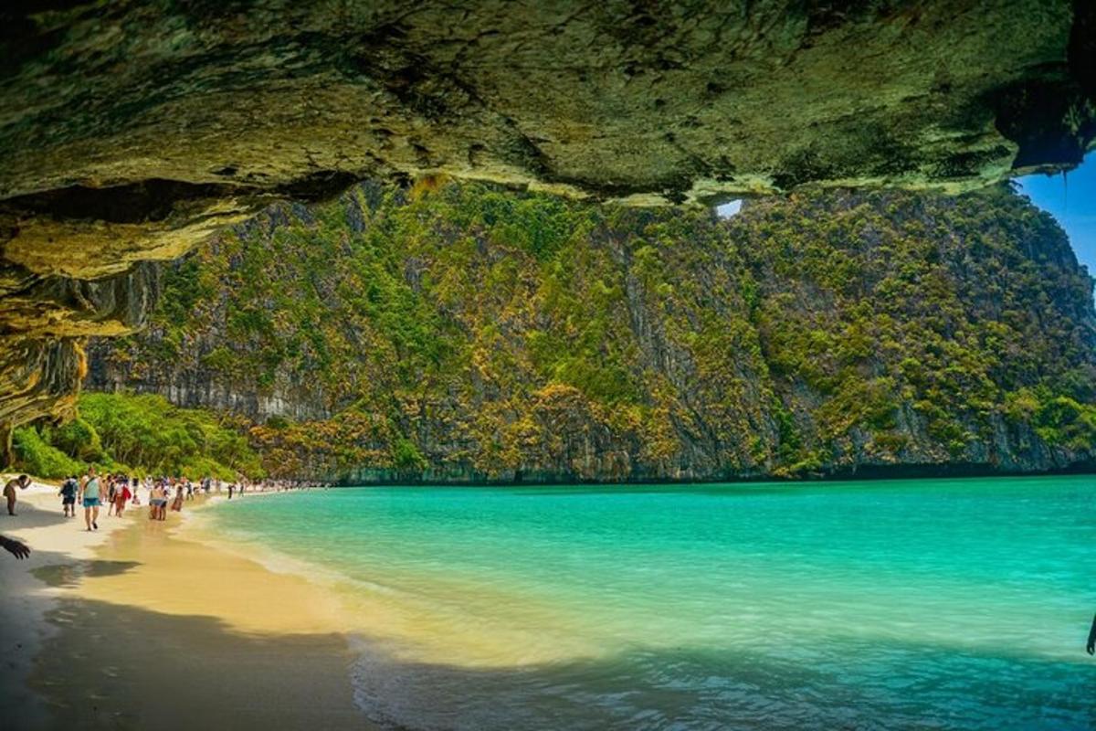 skupina ljudi, ki hodijo po plaži v bližini jame
