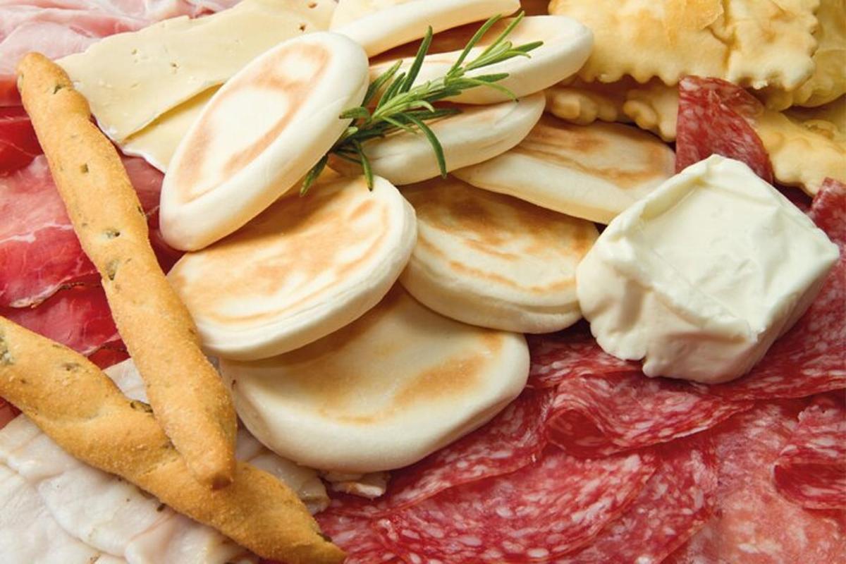 Un plato de comida con queso y carnes y papas fritas.