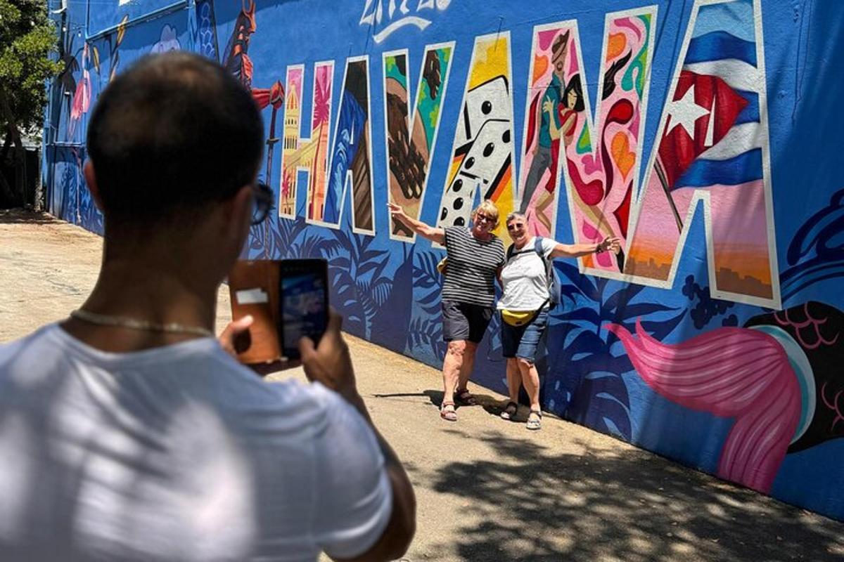 muž fotografující dva lidi, jak malují zeď