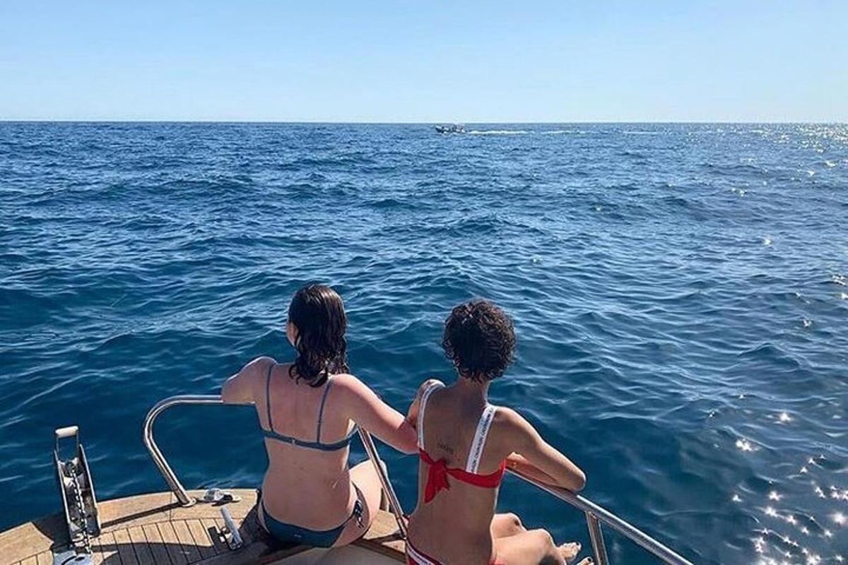 kaks bikiinides naist istuvad paadis vees