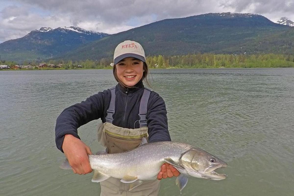 una giovane ragazza che tiene in mano un pesce in un lago