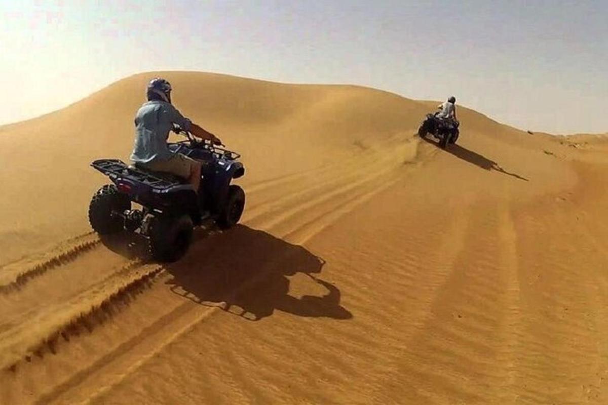 dua orang menunggang basikal quad di padang pasir