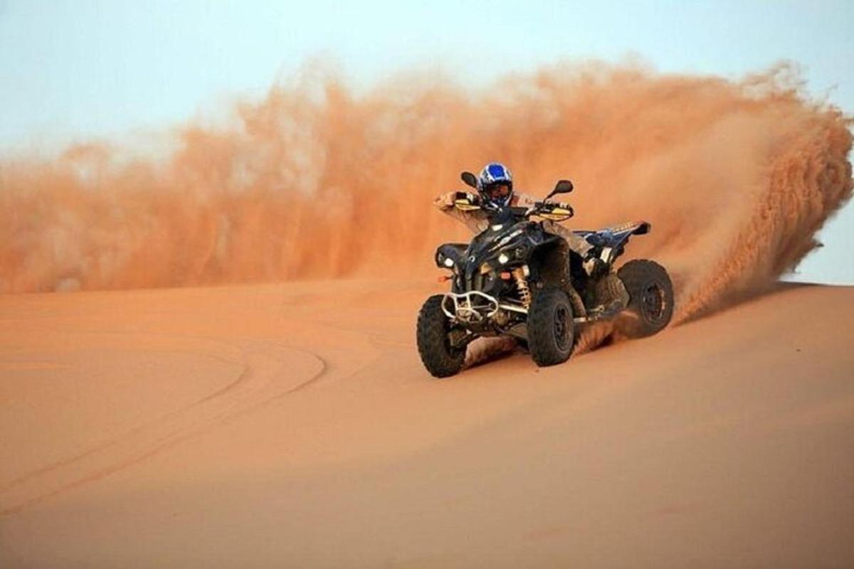 seseorang yang menunggang basikal quad di padang pasir