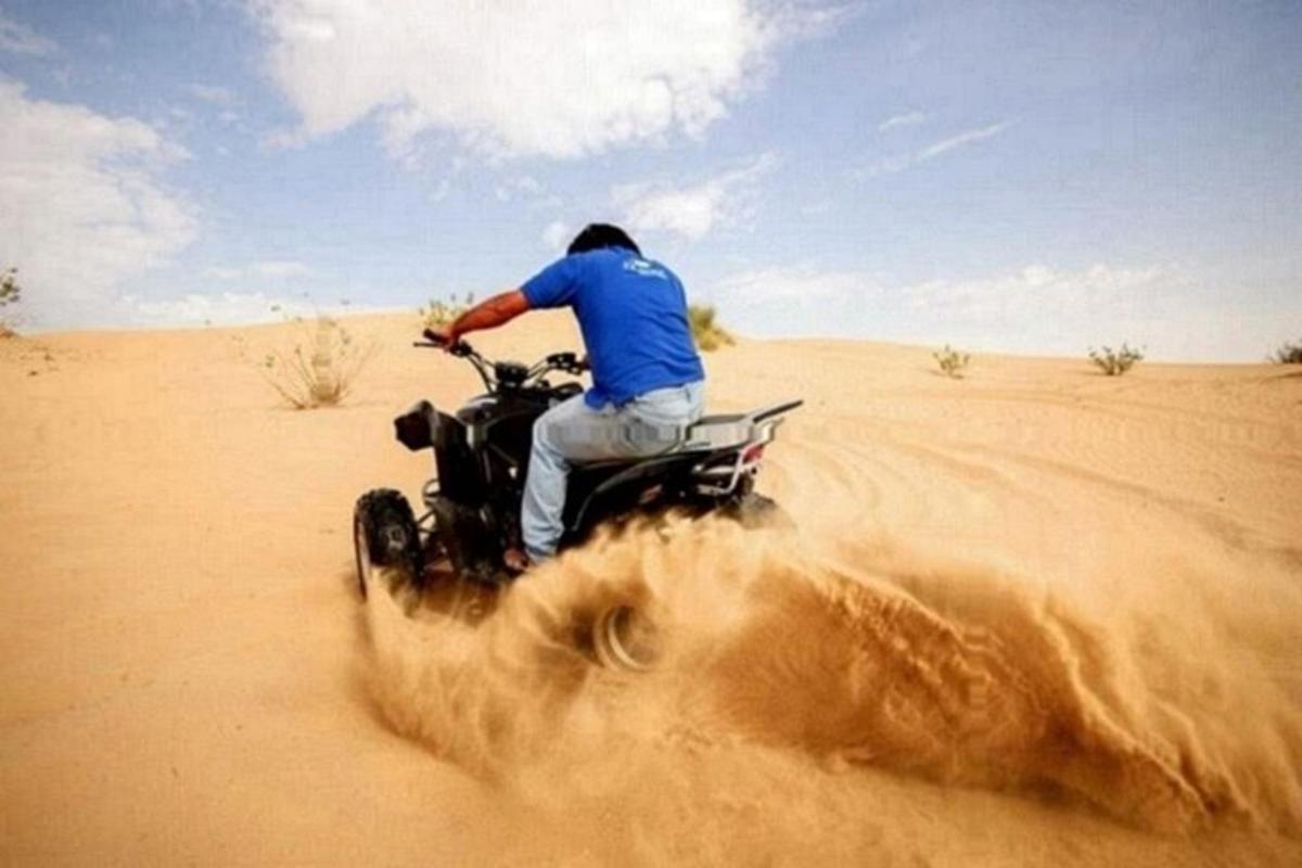 Un hombre conduciendo una motocicleta todoterreno en el desierto.