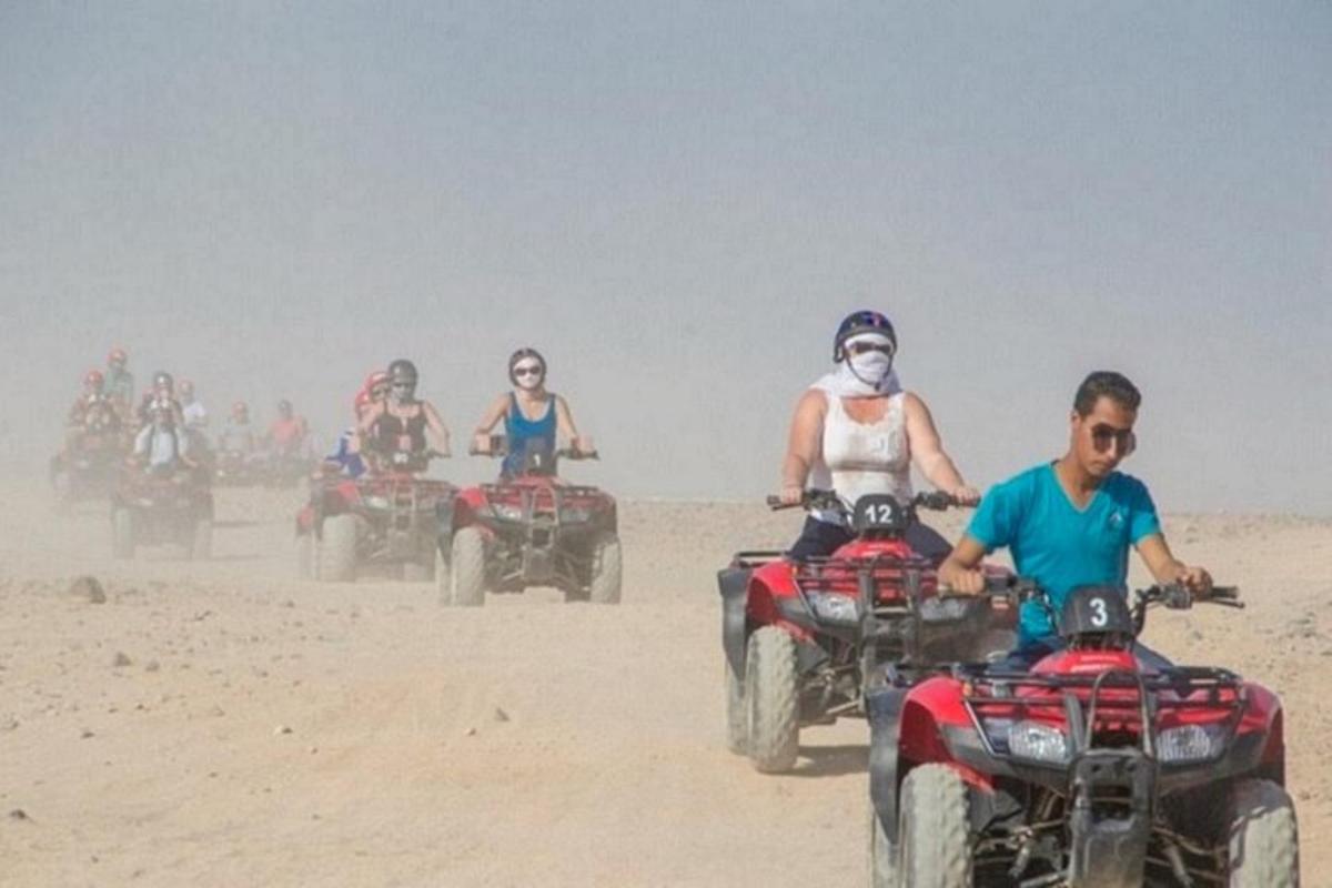 Un grupo de personas conduciendo vehículos todo terreno en la arena.