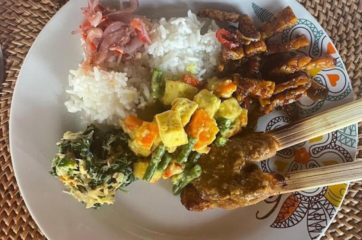 sepinggan makanan dengan nasi dan sayur-sayuran dan penyepit