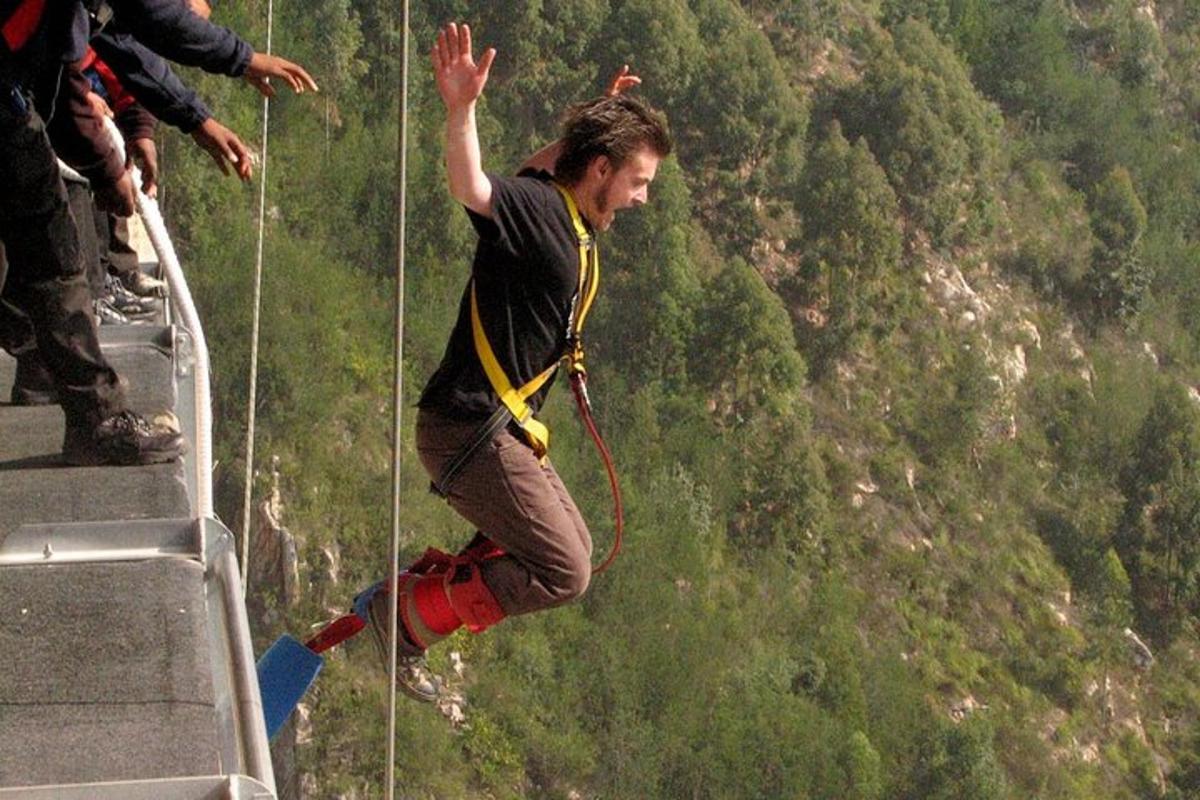 a man hanging from a rope on a zip line