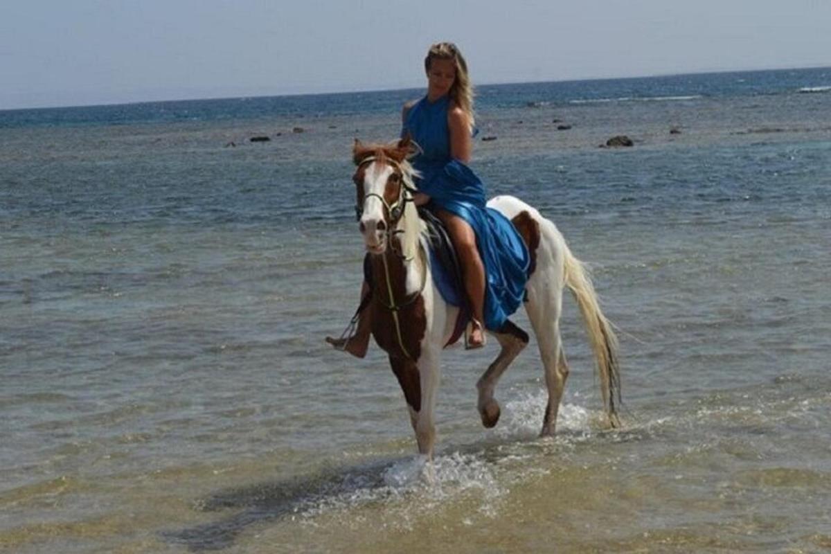 een vrouw die op een paard op het strand rijdt