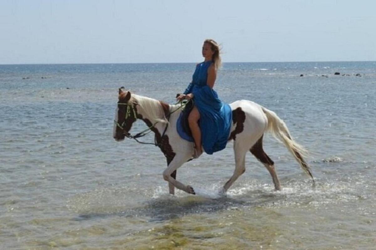 žena jedoucí na koni na pláži