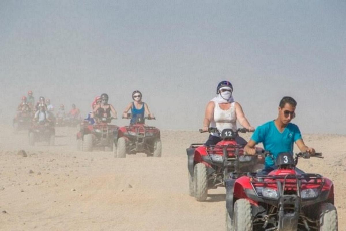 um grupo de pessoas andando de quadriciclo na areia