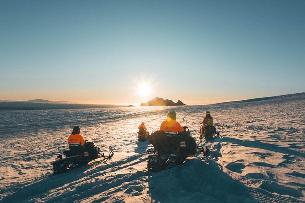 un grup de oameni care merg pe ATV-uri prin zăpadă