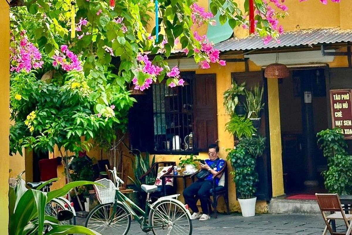 seorang lelaki duduk di meja di luar bangunan dengan basikal