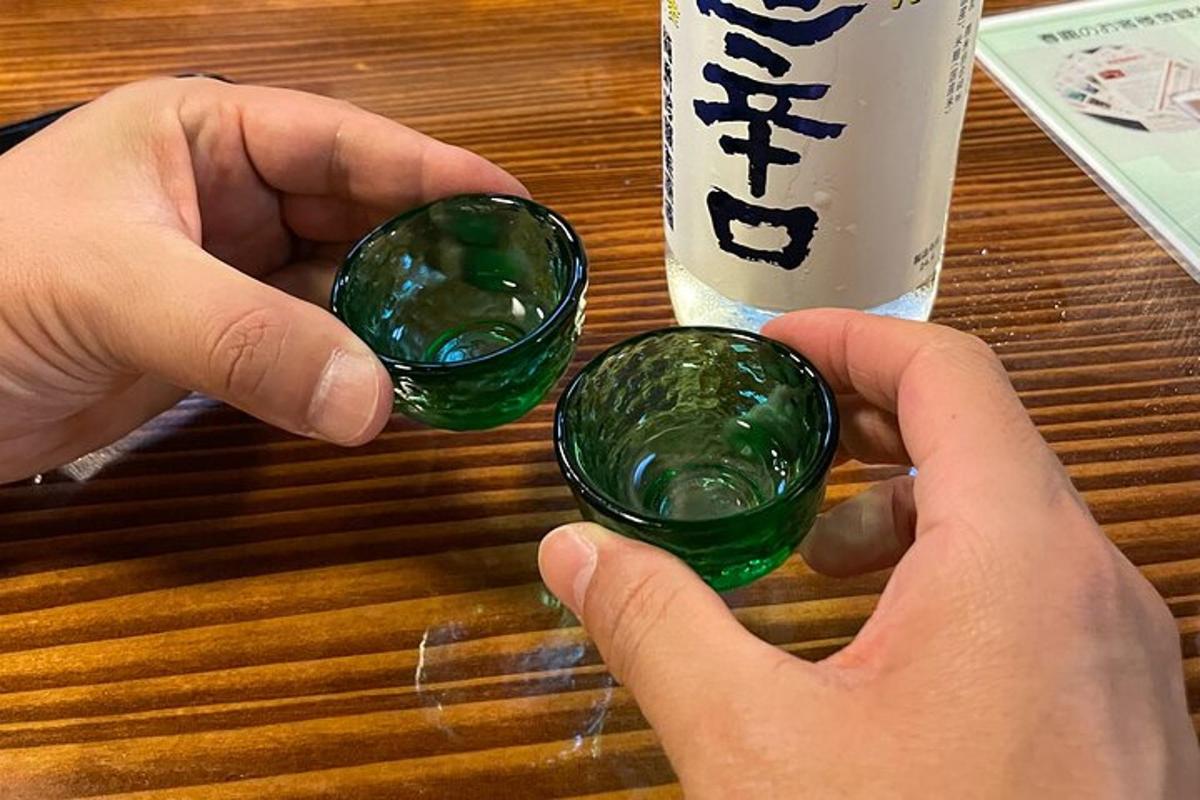 two hands holding green glass spheres next to a drink
