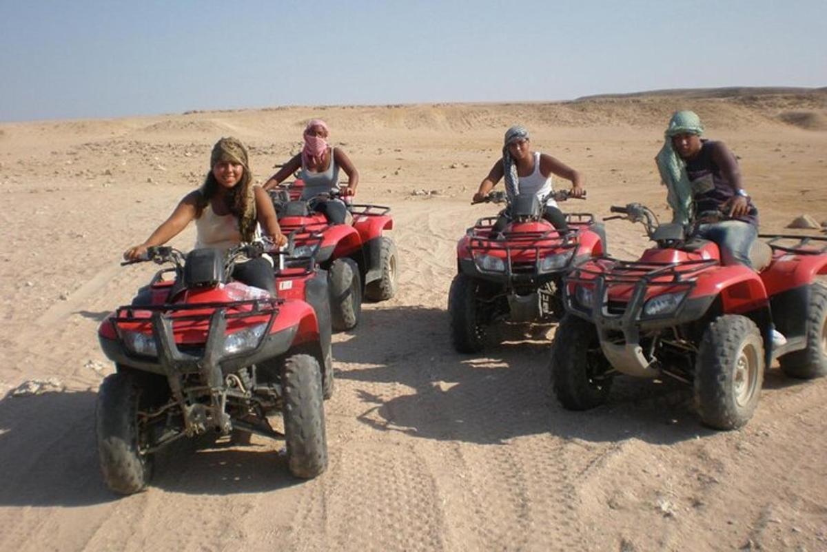 um grupo de pessoas andando de quadriciclo no deserto