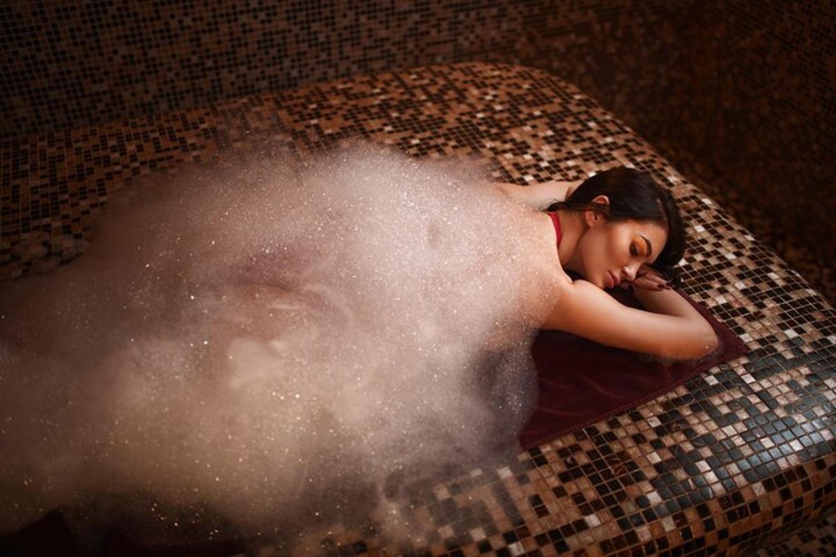 seorang wanita berbaring di bak mandi dengan kepulan asap