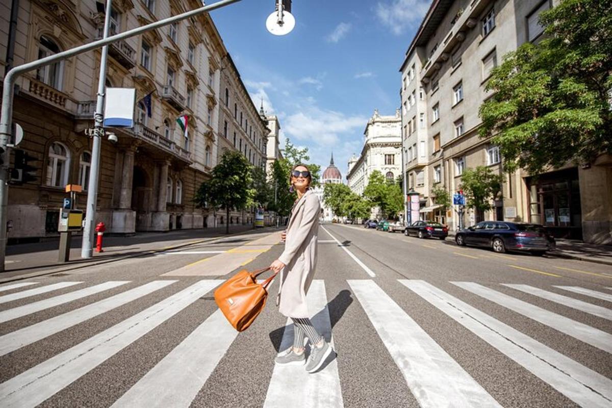 a man walking across a street with an orange bag