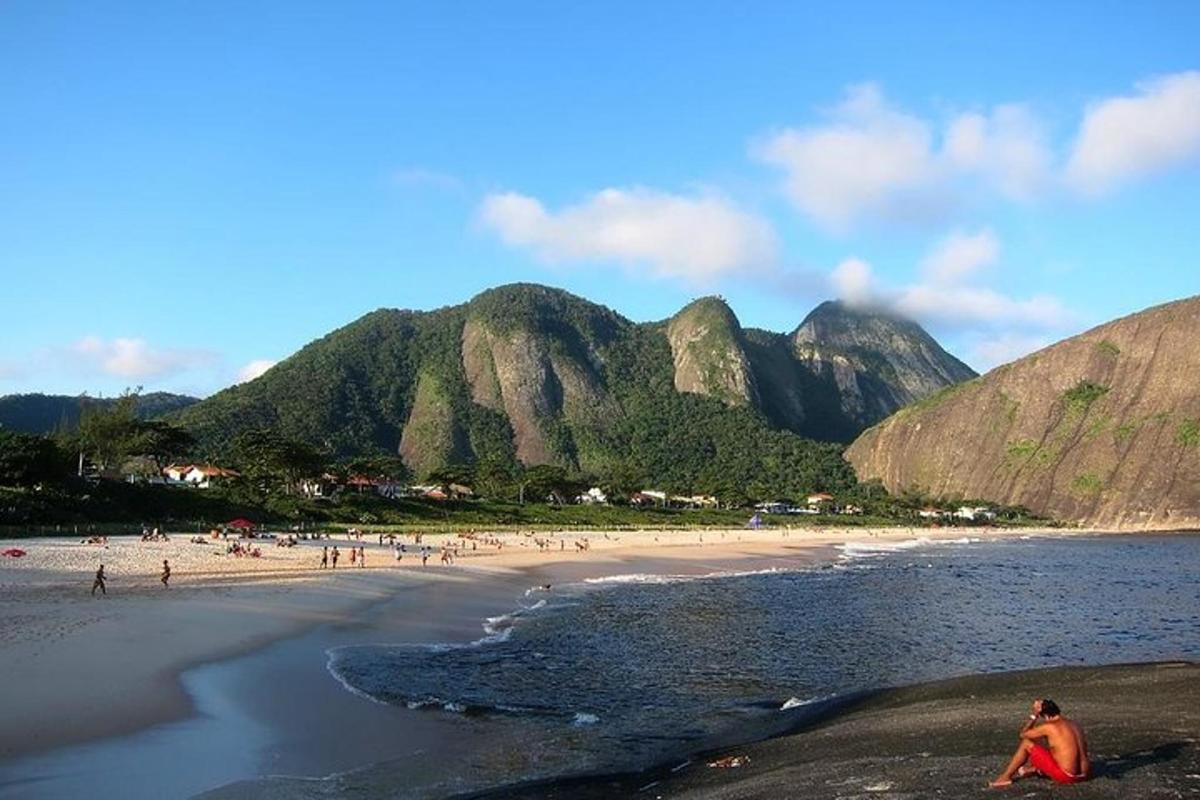 sekumpulan orang di pantai dengan latar belakang gunung