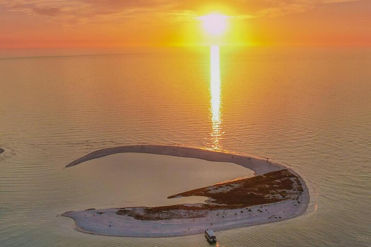 sebuah pulau di tengah-tengah air dengan matahari terbenam