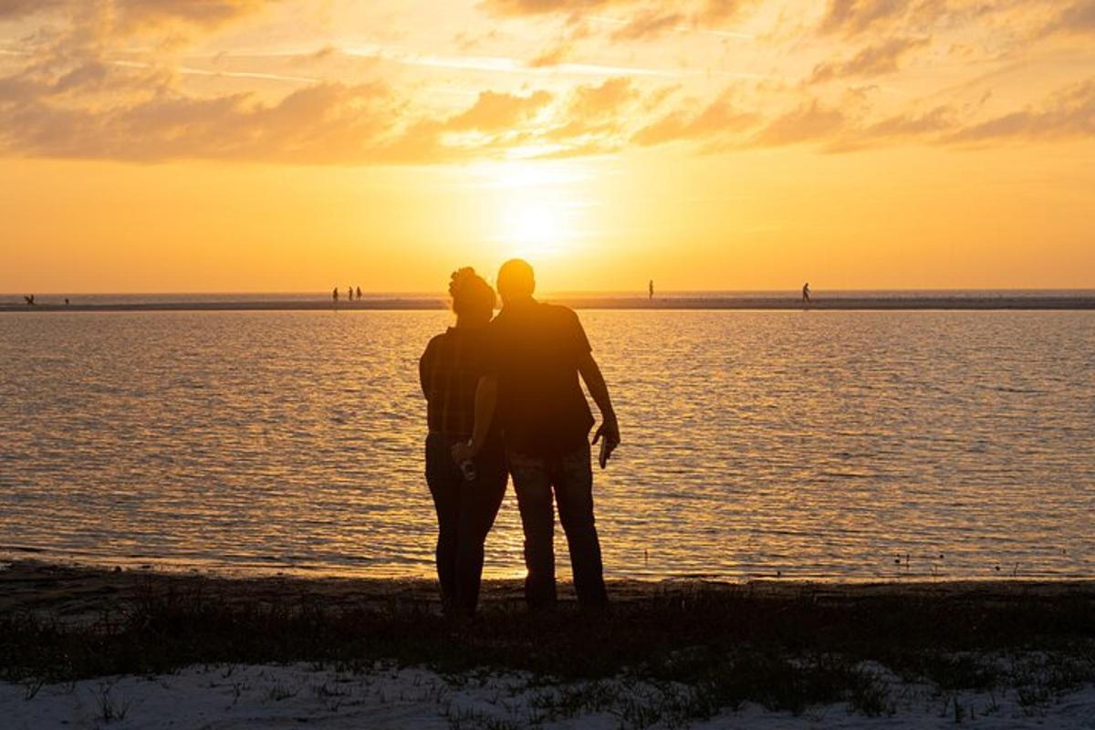 un uomo e una donna in piedi sulla spiaggia al tramonto