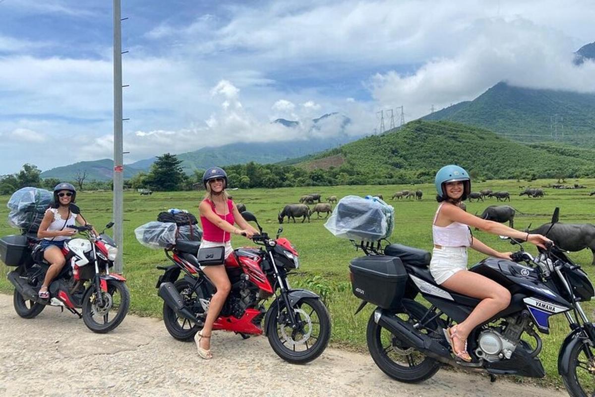 Három nő ül motorokon egy mező előtt