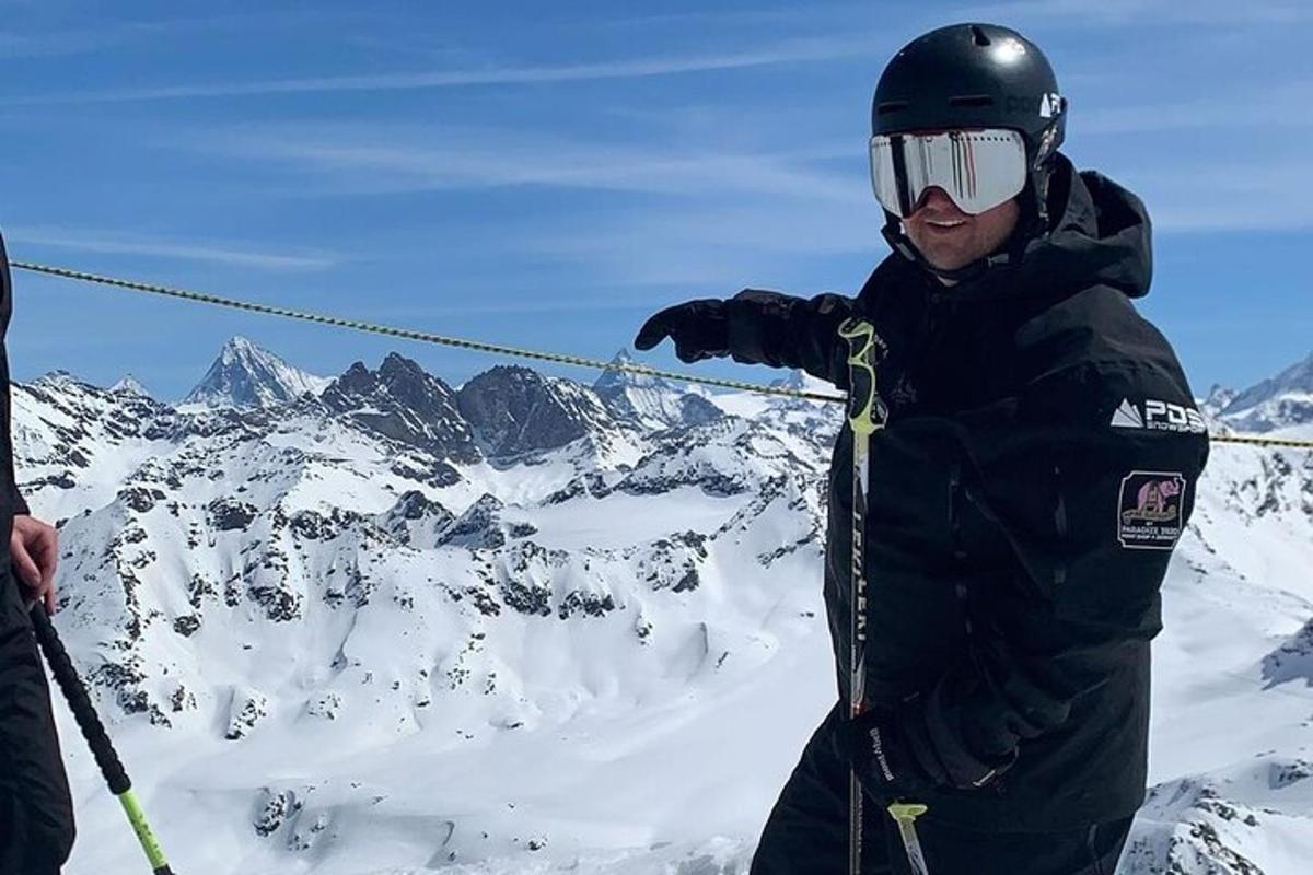 um homem em pé no topo de uma montanha coberta de neve