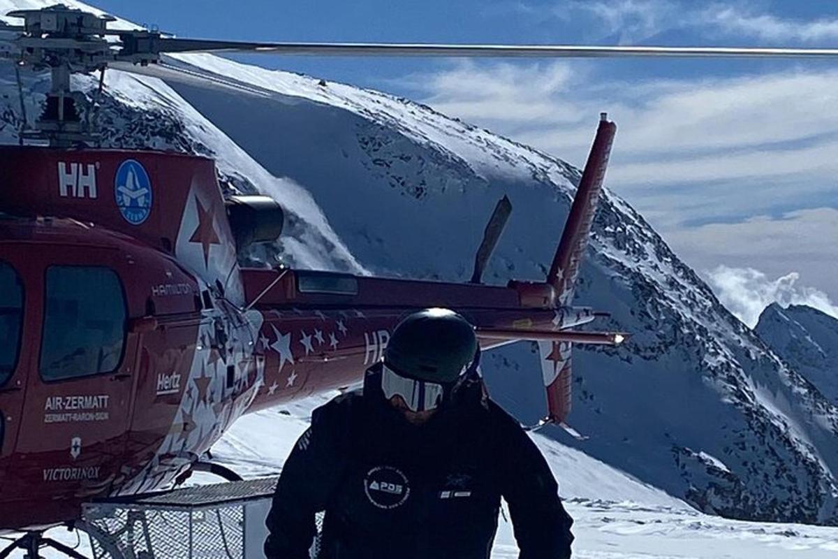 een man die naast een helikopter in de sneeuw staat