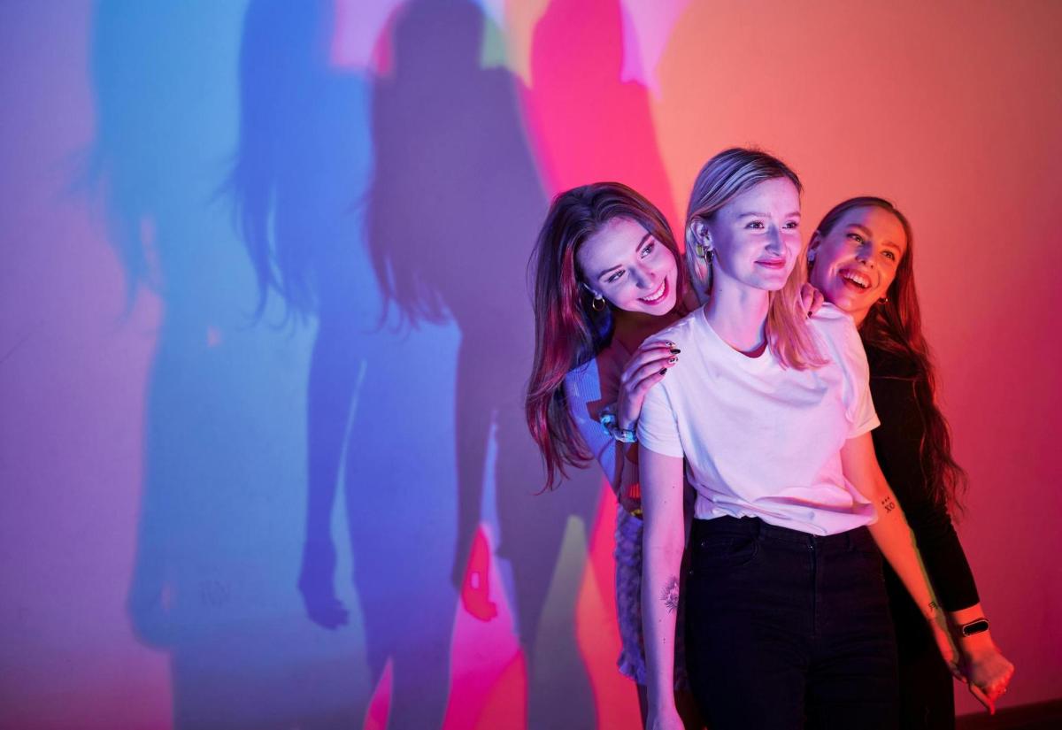 three girls standing in front of a colorful wall