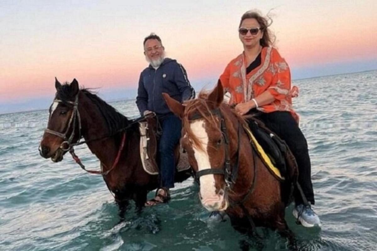 two people riding a horse in the water