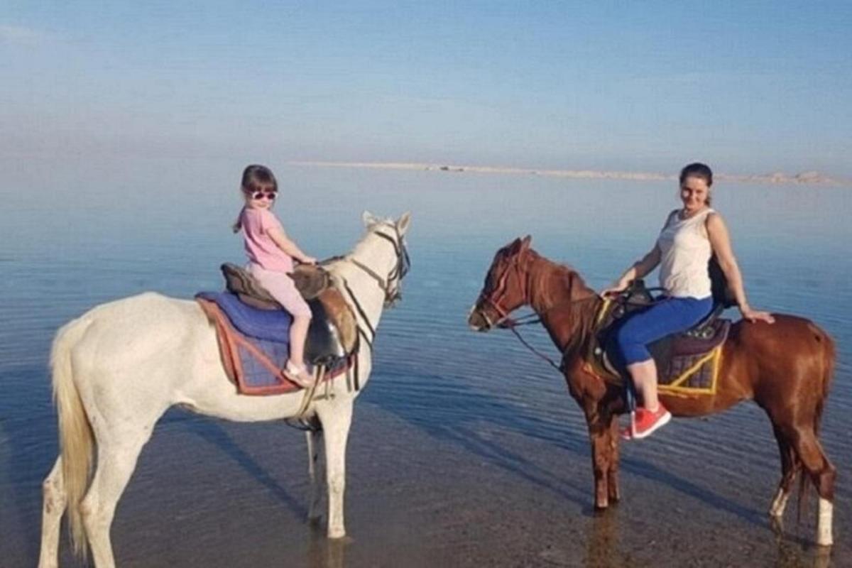 una donna e una ragazza a cavallo sulla spiaggia
