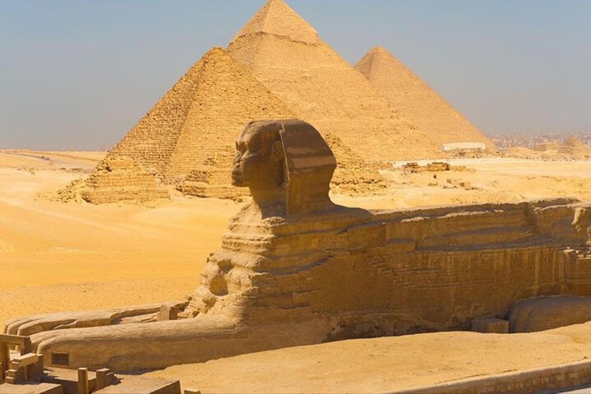 ένα άγαλμα μπροστά από τις πυραμίδες στην έρημο