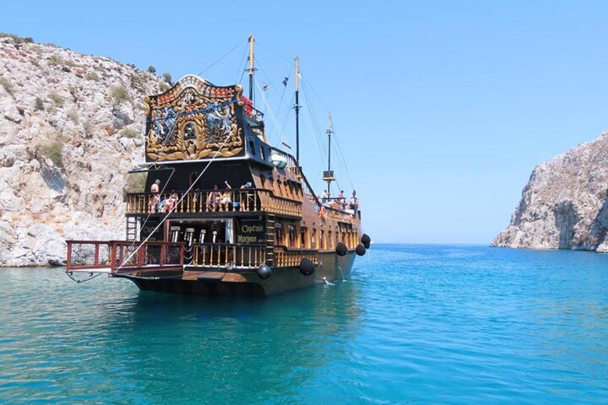 a large boat in the water next to a cliff