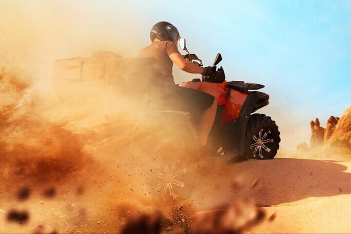 seorang lelaki menunggang basikal quad di padang pasir