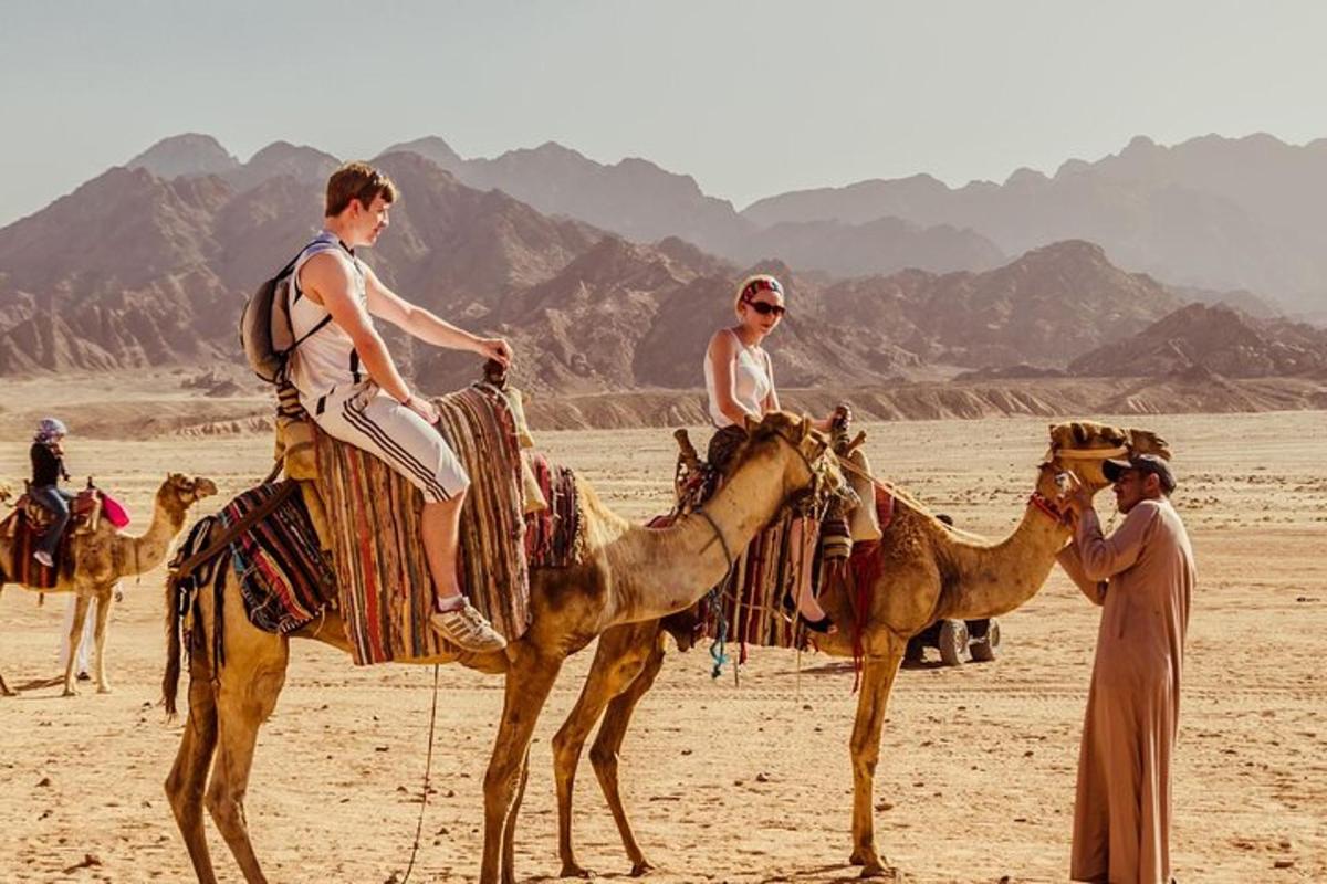 due persone a cavallo sui dorso dei cammelli nel deserto