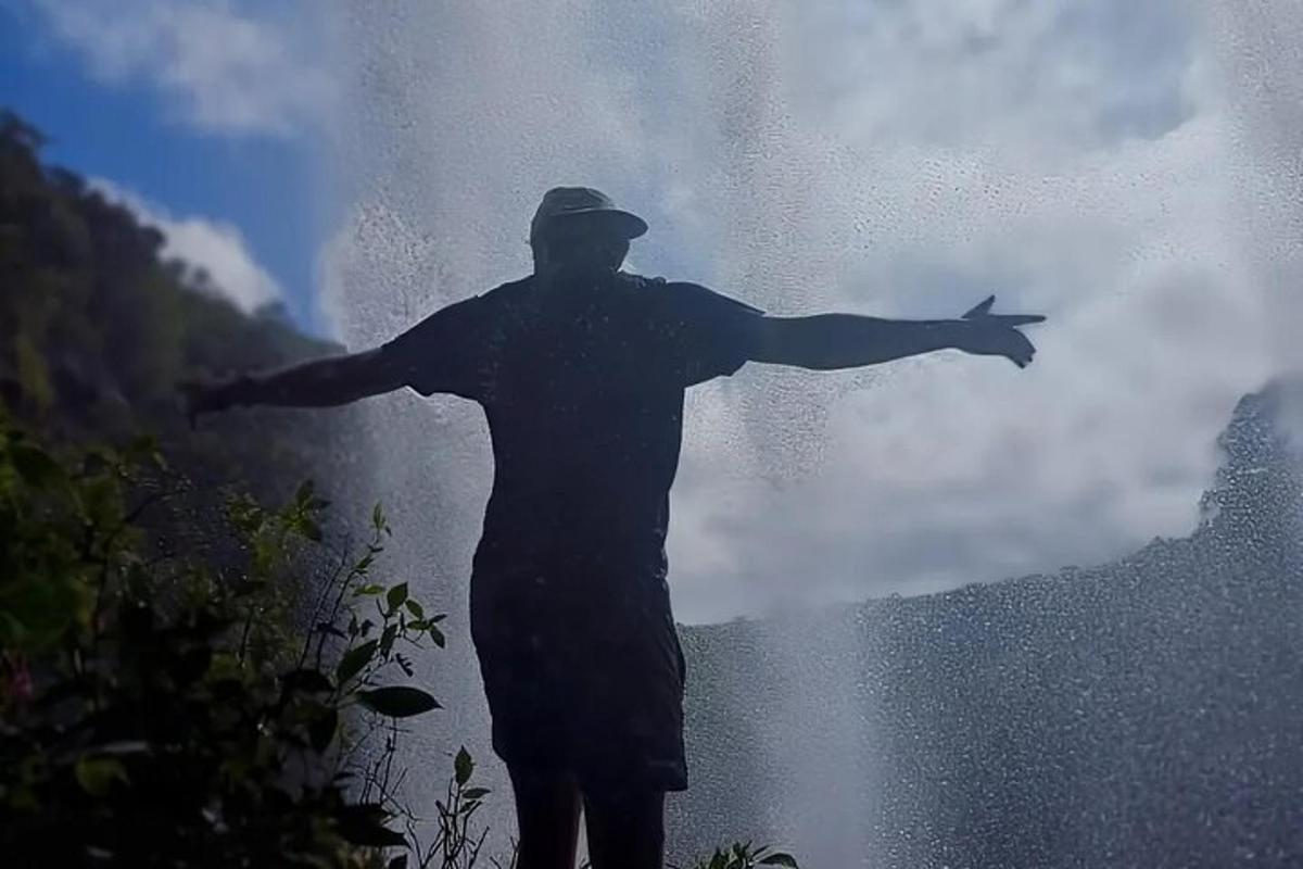un uomo in piedi con le braccia tese davanti a una cascata