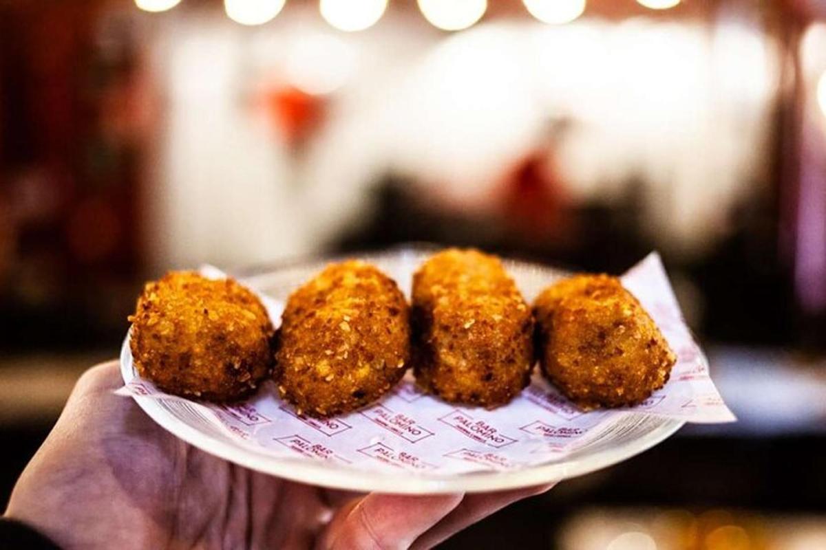 una persona sosteniendo un plato con cuatro alimentos fritos