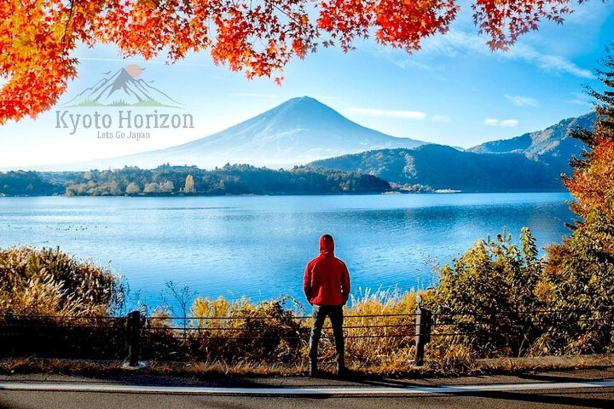 a man standing in front of a lake with a mountain
