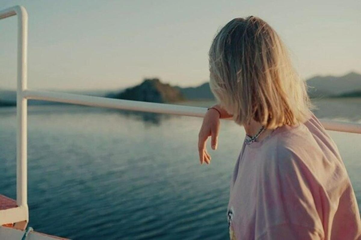 una giovane ragazza in piedi su una barca vicino all'acqua