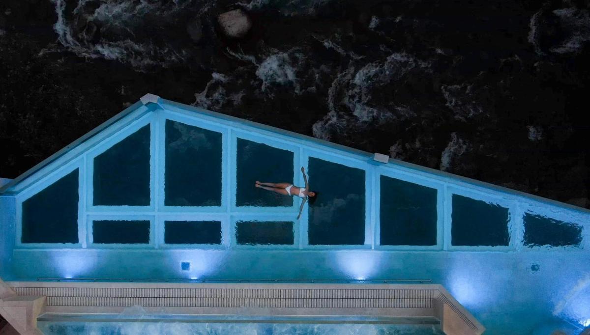 una persona che nuota in una piscina di notte
