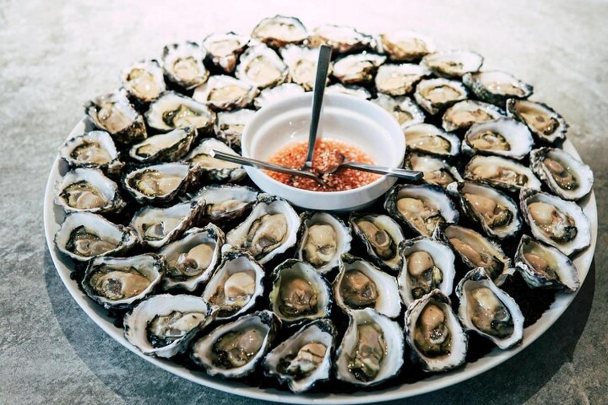 a plate of oysters with a bowl of sauce