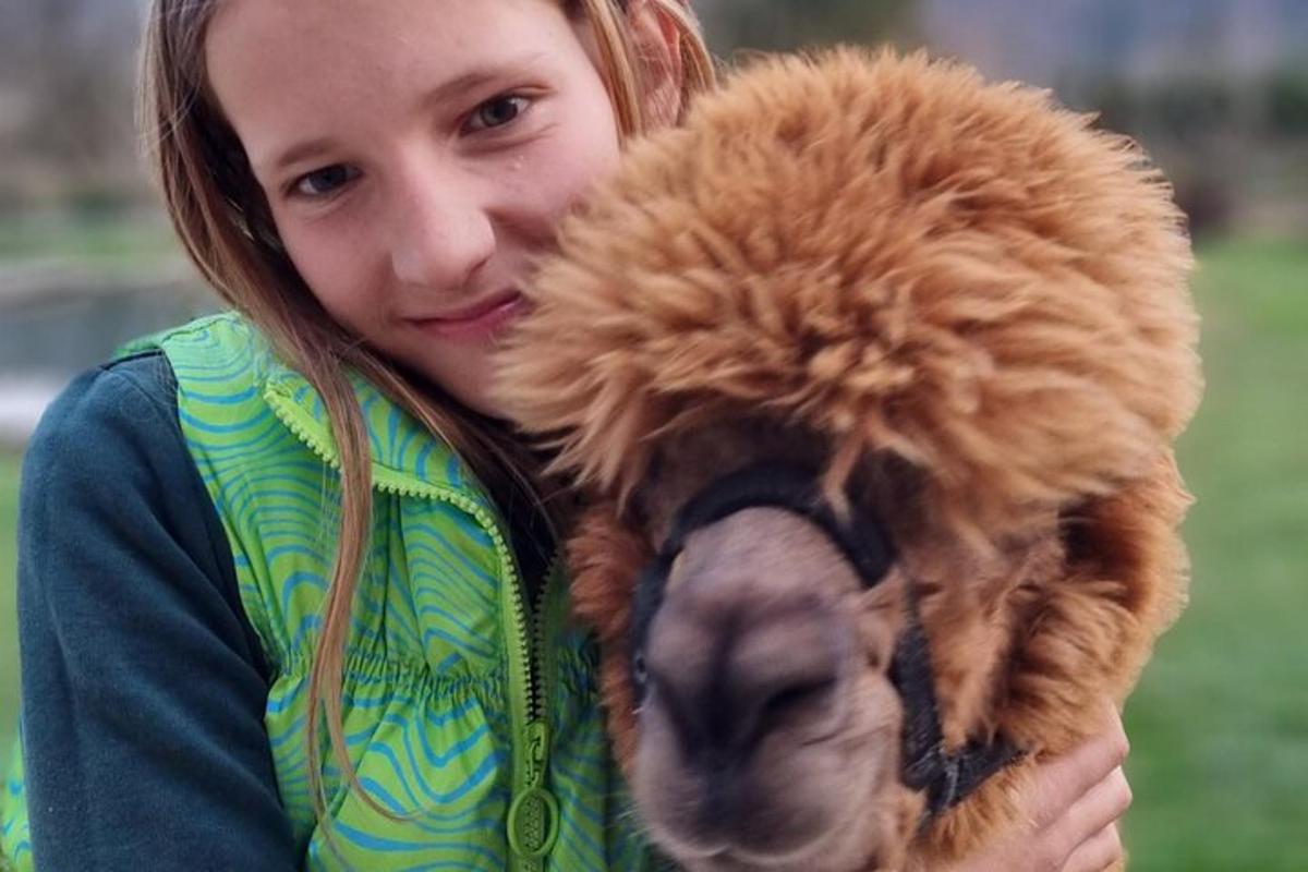 Una mujer joven sosteniendo un perro marrón en sus brazos