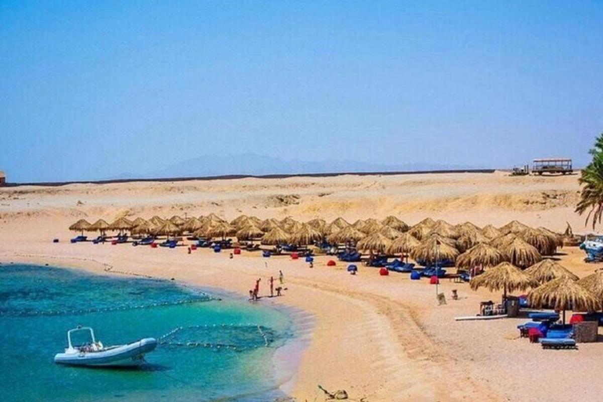 una spiaggia con ombrelloni di paglia e una barca su di essa