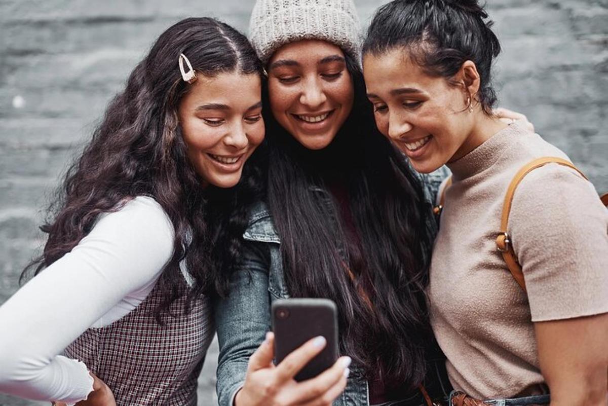 tre donne che ridono mentre guardano un cellulare