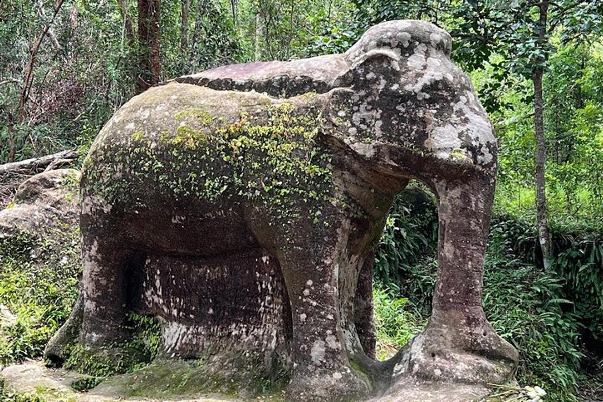 a statue of an elephant standing in the woods