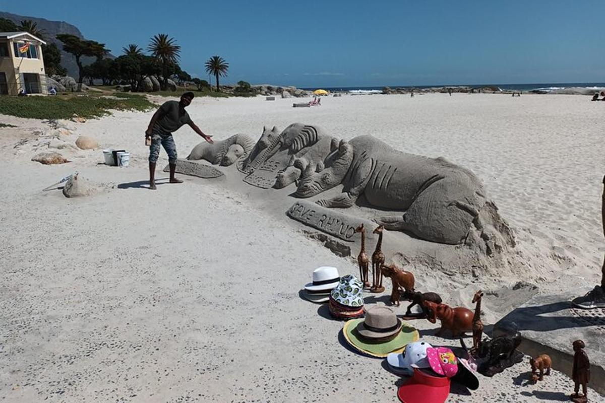 un home fent una escultura de sorra a la platja