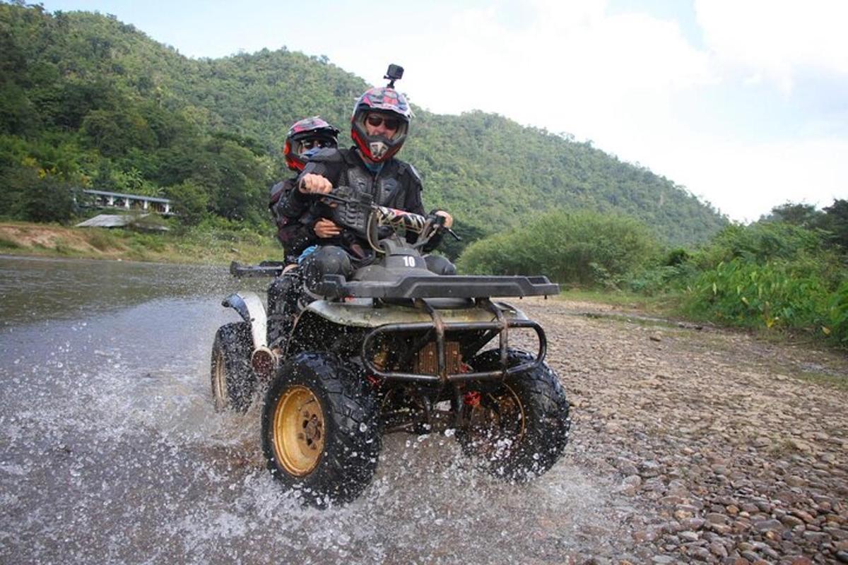 Dos personas en un vehículo de cuatro ruedas cruzando un río